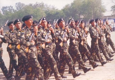 Rows of commandos in camouflage and black berets marching in parade formation with rifles