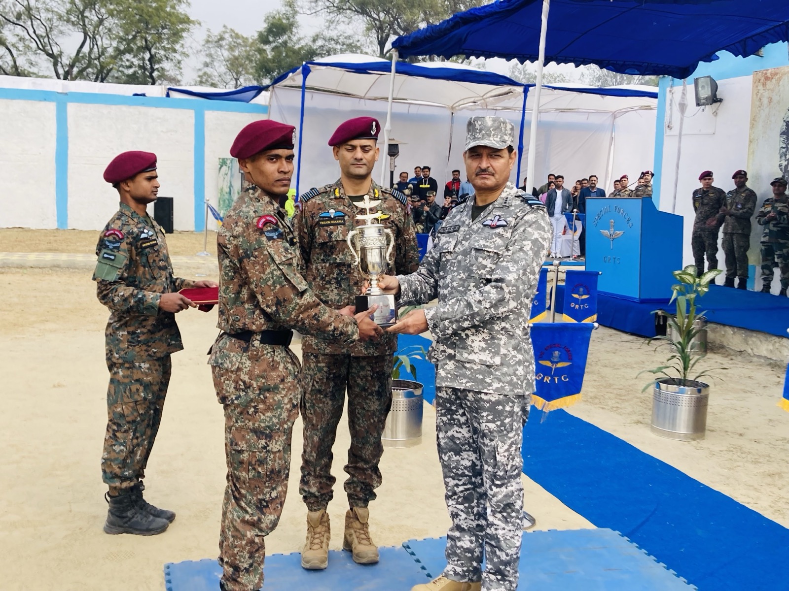 Maroon-beret commandos receiving a silver trophy from a senior officer at a ceremony