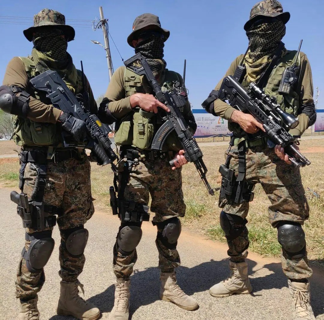 Three Garud commandos in full tactical gear with shemaghs and rifles standing ready outdoors