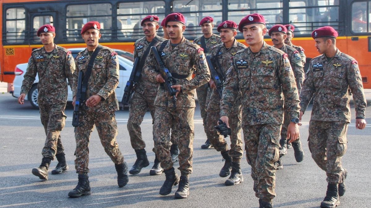 Contingent of maroon-beret special forces personnel in digital camouflage marching in formation on a city road